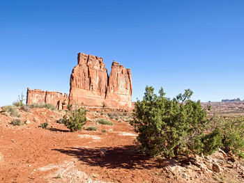 Rock formations on landscape against clear blue sky