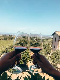 Cropped hand holding glass of water against clear sky