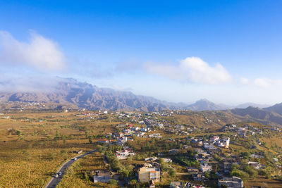 Aerial view of townscape and mountains against sky