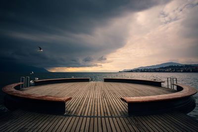 Empty pier over sea against sky at sunset