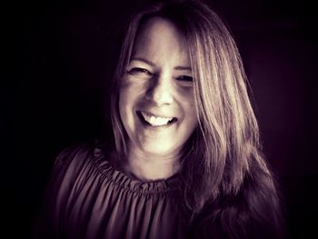 Portrait of smiling young woman against black background