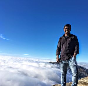 Portrait of man standing against cloudy sky