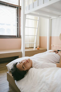 Woman lying on bed at home