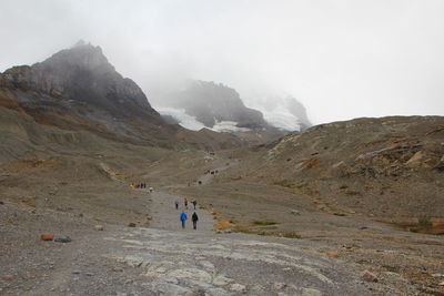 People walking on mountain against sky