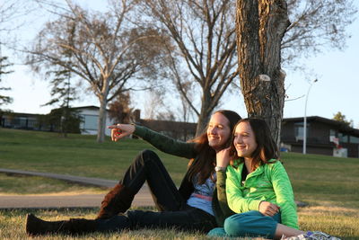 Happy couple sitting on grass against trees