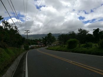 Country road against cloudy sky