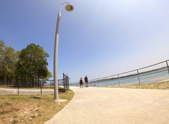 People on street by sea against clear sky