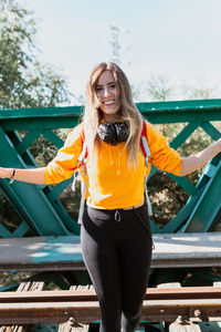 Portrait of smiling woman standing on railroad track