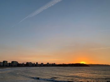 Scenic view of sea and buildings against sky during sunset