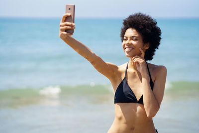 Portrait of young woman taking selfie at beach