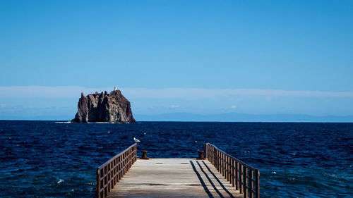 Pier over sea against blue sky