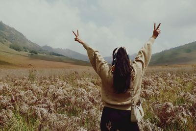 Rear view of woman standing on field against sky