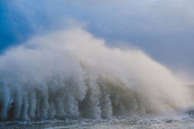 Waves splashing on shore against sky