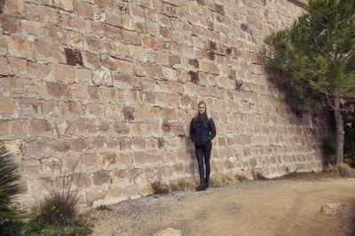 Full length of woman standing against wall