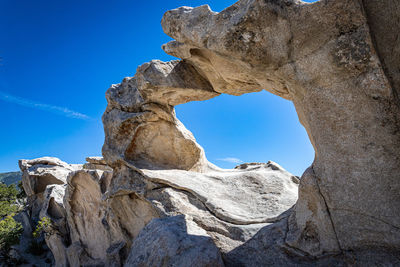 Low angle view of rock formation against clear blue sky