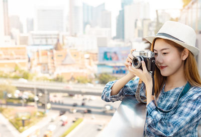 Young woman photographing with camera in city