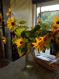 Flower vase on table by window at home