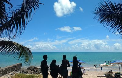 People standing on beach against blue sky