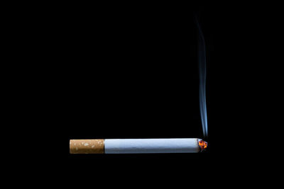 Close-up of cigarette smoking against black background