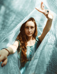 Portrait of beautiful young woman with arms raised