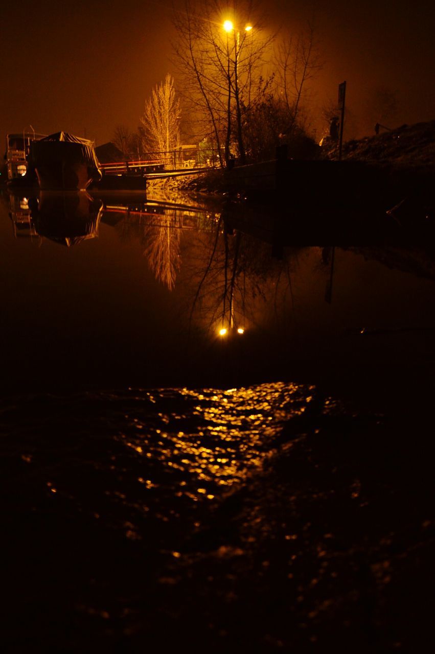 illuminated, night, reflection, water, sunset, street light, silhouette, river, lighting equipment, sky, tree, lake, transportation, tranquility, dark, nature, outdoors, dusk, bare tree, tranquil scene