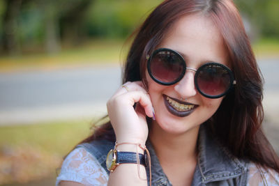 Close-up portrait of smiling young woman wearing sunglasses