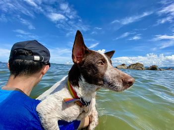 Man with dog in sea against sky