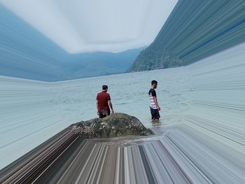 People on sea by mountain