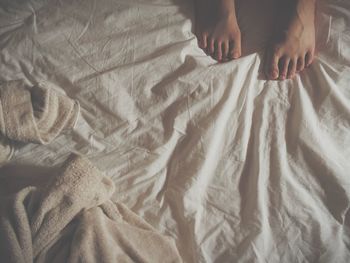 Low section of woman sitting on bed