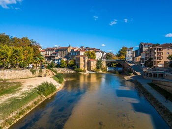 River amidst buildings against blue sky