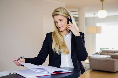 Businesswoman talking on smart phone while working in office