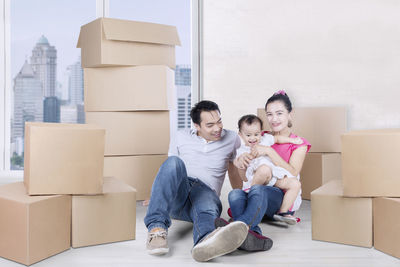 Happy parents and daughter sitting in new home