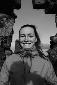 Portrait of young woman standing against rock