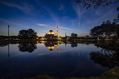 Panoramic view of illuminated building by lake against sky