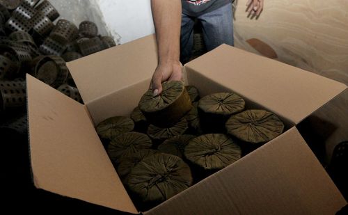 Midsection of worker keeping covered containers in box