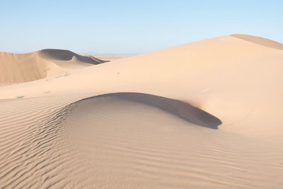 Sand dunes in desert against clear sky