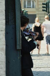 Street musician playing violin against wall