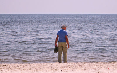 Rear view of senior man standing at beach during summer