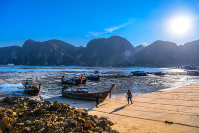 People on beach by mountains against sky