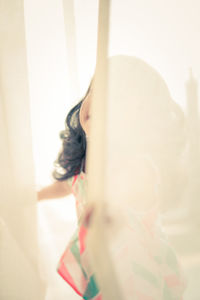 Close-up of woman standing by window at home