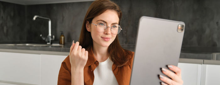 Young woman using mobile phone while sitting on table