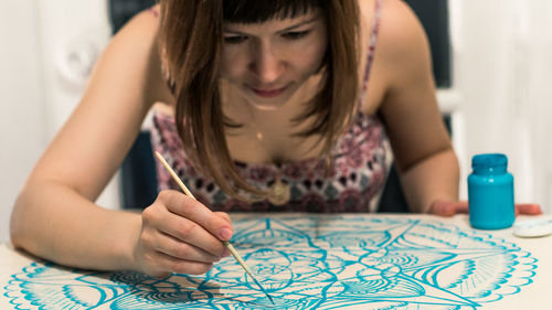 Midsection of woman sitting on table at home