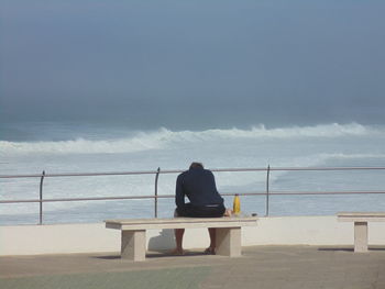 Rear view of man sitting on promenade against sky