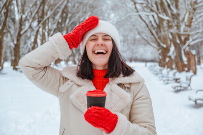 Portrait of smiling young woman standing on snow covered field