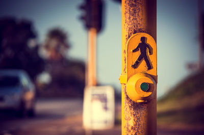 Close-up of road sign with push button on pole