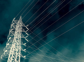 Low angle view of electricity pylon against sky at night