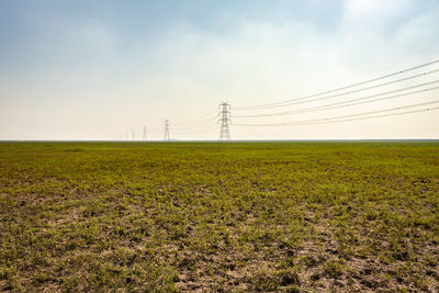 Electricity pylon on field against sky