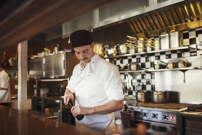 Waiter holding pepper mill at restaurant