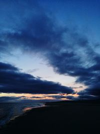 Scenic view of sea against dramatic sky during sunset