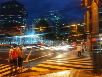 People walking on illuminated city street at night